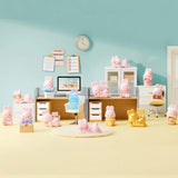 MOMO Bunny 24h Work Life Diary - Blind Box with pastel pink and gold MOMO Bunny figures in a colorful office display.