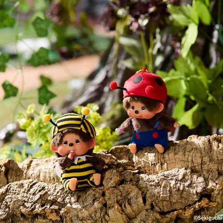 Bee costume bag charm: striped yellow-and-black plush bee figure with gold chain, resting on a rock