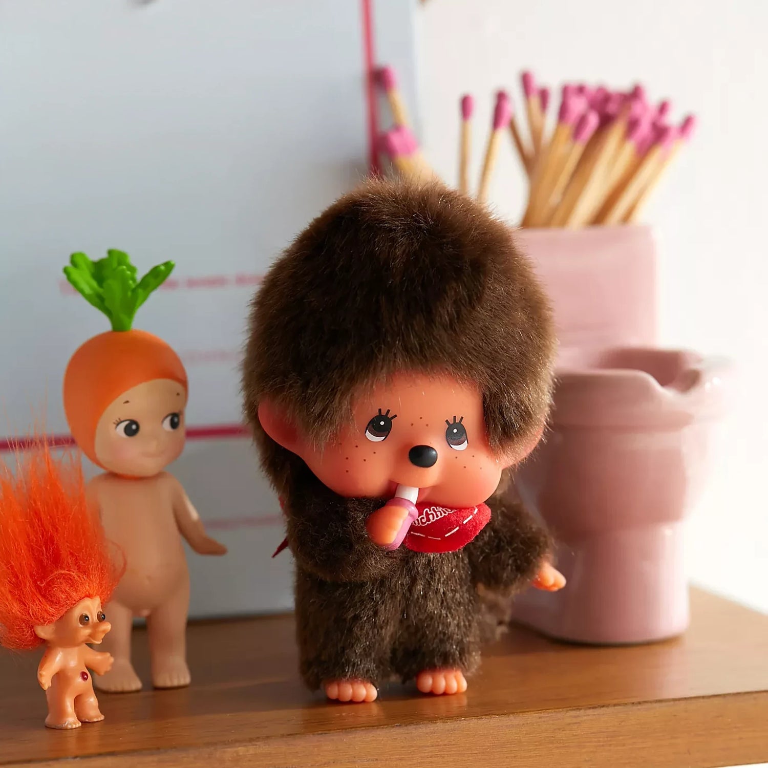Standing brown plush bag charm boy with red shirt, clasped hands, side angle