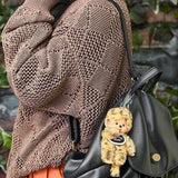 Leopard-pattern plush bag charm on a black handbag, with beaded chain
