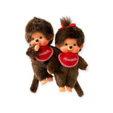 Two Monchhichi dolls with brown fur and red bibs exude vintage vibes. The nostalgia is palpable as the Twin Boy Plush Doll and another with a red ribbon evoke cherished childhood memories.