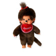 The Monchhichi Plush Doll - Twin Girl by Monchhichi is a vintage collectible with soft brown fur, a red bow, a red bib with white lettering, and an adorable tuft of hair, perfect for enthusiasts.