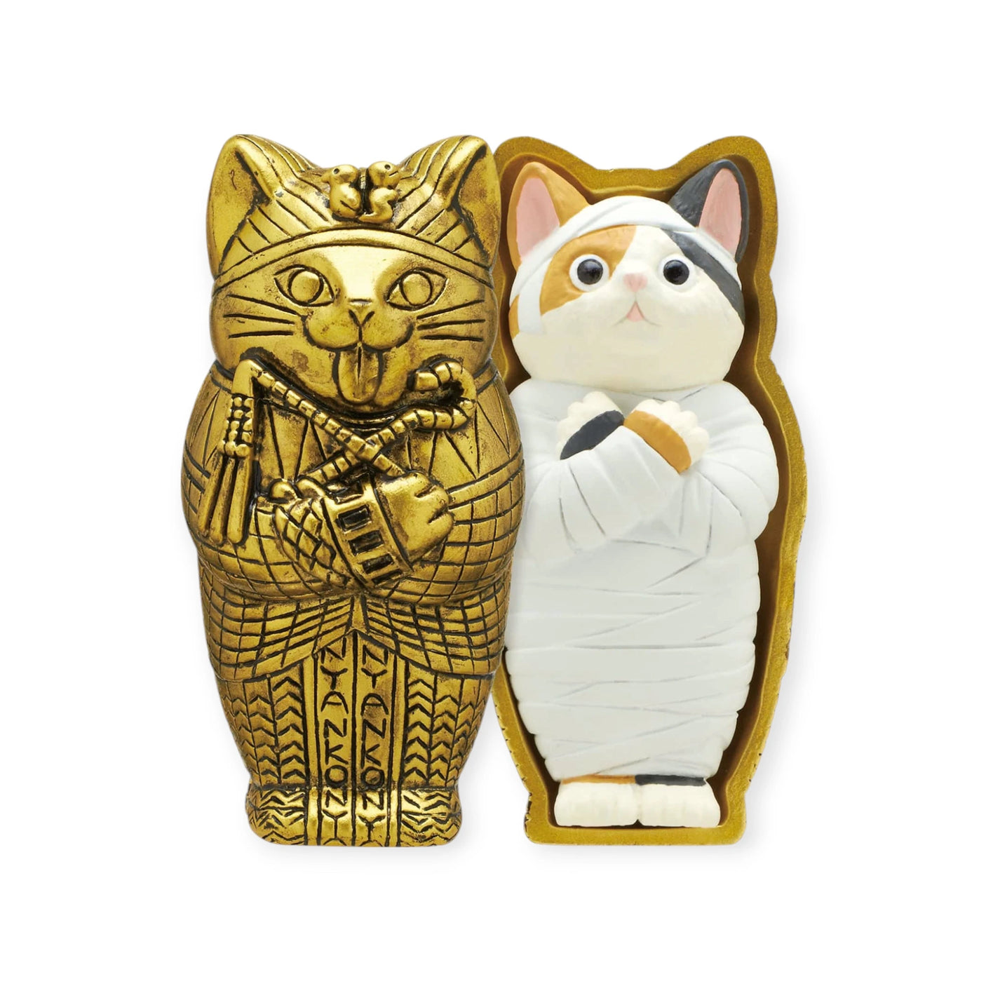 The Kitan Club Mummy Cat Blind Box features two cat-shaped figurines: a gold one resembling a sarcophagus and a white one with bandages, styled as an ancient Egyptian mummy cat. Perfect for a surprise!