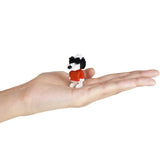 A miniature brick figure, part of the Nanoblock Peanuts Blind Bag - Vol. 3 collection, resembling a dog wearing sunglasses and a red shirt, is displayed on an open hand against a white background.