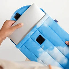 A person inserts a laptop into a blue cloud-patterned padded sleeve.