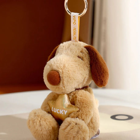 Beige plush dog keychain with brown ears holding gold star labeled LUCKY attached to fabric loop and metal ring