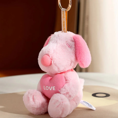 Soft pink plush dog keychain holding bright pink heart with LOVE text hanging from gold ring