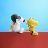 White plush pilot dog with brown helmet and yellow scarf, with small yellow toy dog beside.