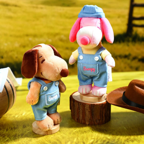 Two plush dog keychains in light denim overalls with stitched name patches, on bases