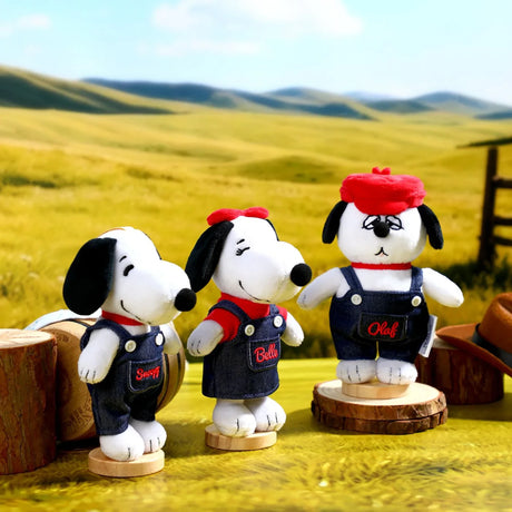 Three Snoopy-style plush keychains in dark denim overalls on wooden stumps