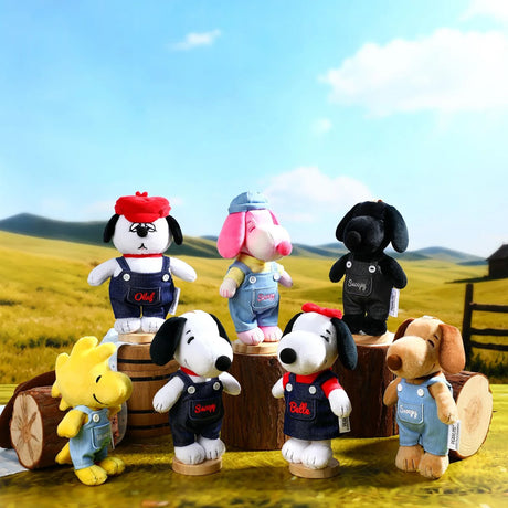 Collection of plush Peanuts keychains in denim overalls standing on wooden stumps