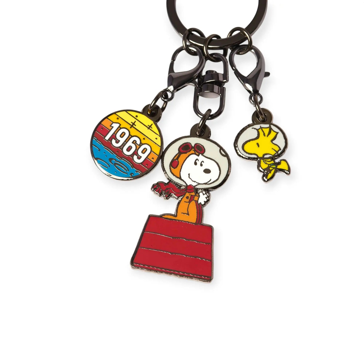 The Snoopy & Woodstock in Space Keychain by Snoopy features three charms: a round "1969" charm, NASA Snoopy in an astronaut s