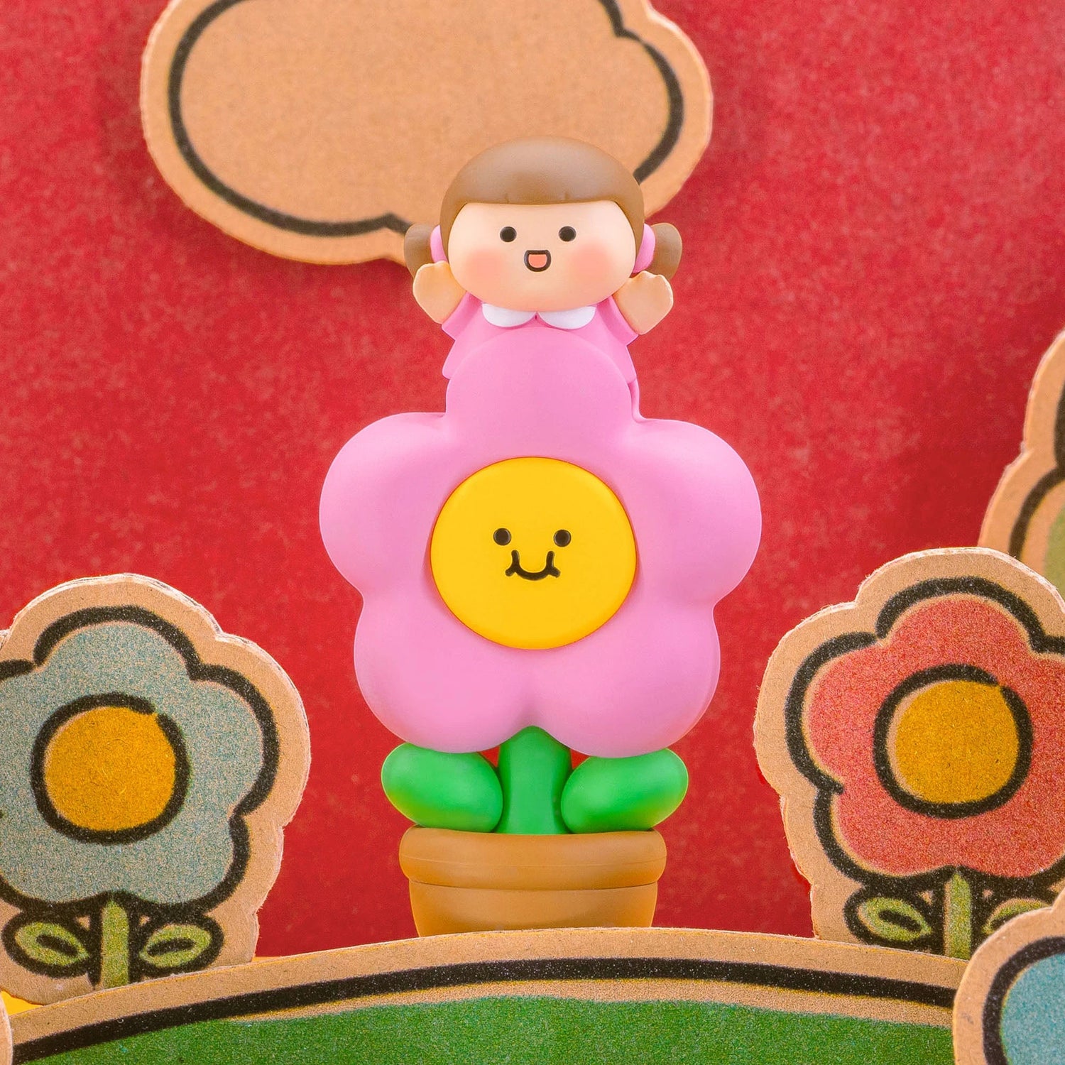 Pink-flower blind-box figurine with smile face, yellow emblem, and green pants.