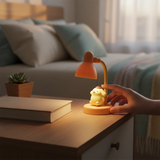 Pompompurin Mini Night Light by Sanrio glowing softly on bedside table beside books and small plant