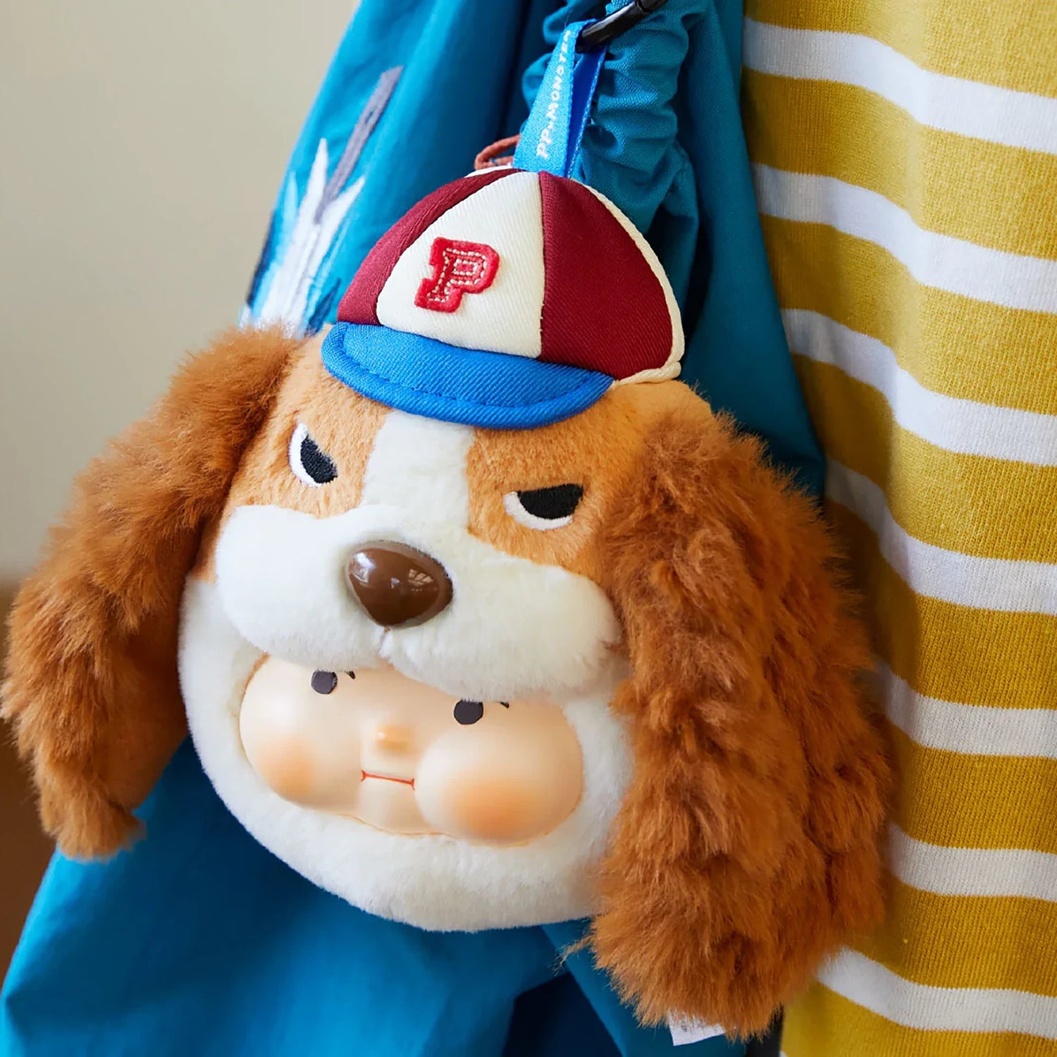 PP x Monster Puppy Bros Plush Keychain - Blind Box showing a plush dog face with a red and white cap by ToyZero+ hanging on a blue bag.