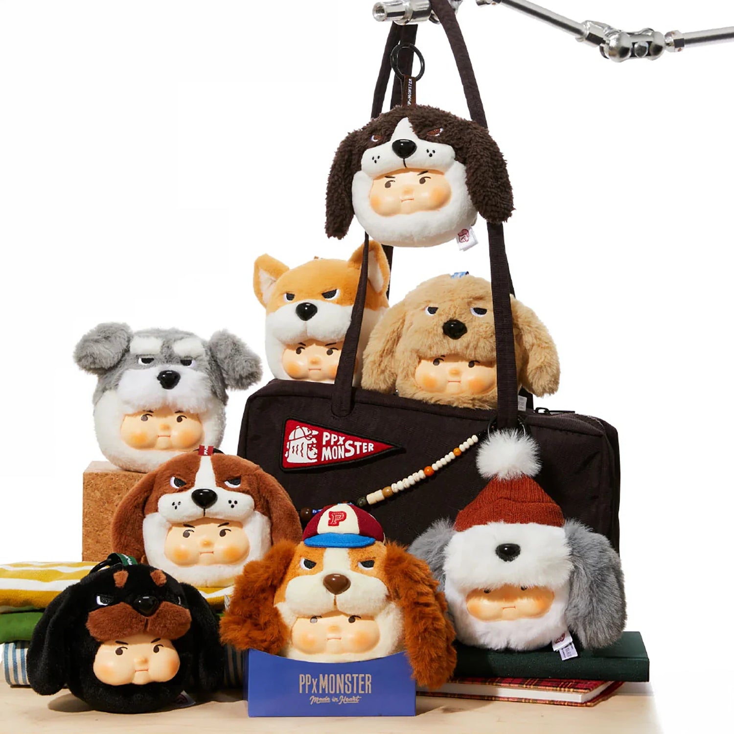 PP x Monster Puppy Bros Plush Keychain - Blind Box showing seven plush dog-faced keychains by ToyZero+ arranged with a bag and books.