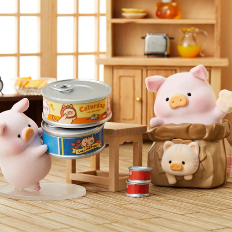LuLu the Piggy figurine holding two stacked cat food cans next to a piggy in cat costume inside a bag on wooden floor
