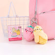 A pink backpack adorned with two adorable plush fruit keychains swings joyfully. Nearby, a wire basket and the Pusheen Blind Box - Fruits Series suggest even more delightful fruity plush treasures to uncover.