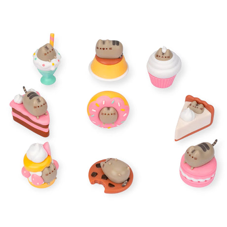 Nine miniature cat figurines styled as desserts like cakes and milkshakes are arranged on a white background. As part of the Pusheen Delicious Desserts - Blind Box collection, these vinyl figures offer delightful surprises.