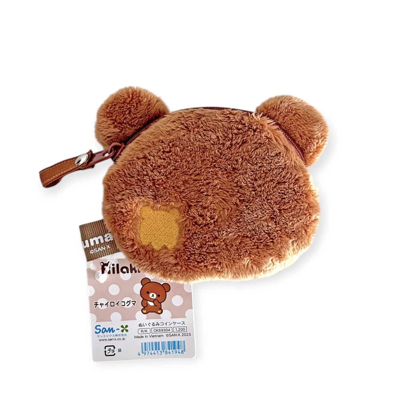 The Rilakkuma - Chairoikoguma Coin Pouch showcases a cute brown bear shape with little ears and a zipper. It includes a tag displaying the beloved bear character and brand details in both Japanese and English.