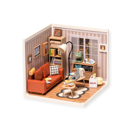 The Rolife Cozy Living Lounge DIY Plastic Mini House by Rolife features a brown sofa, floor lamp, books, wall art, and window. A small table with a coffee cup rests on a circular-patterned rug. Ideal for showcasing your interior design skills or assembling expertise with included decor items.