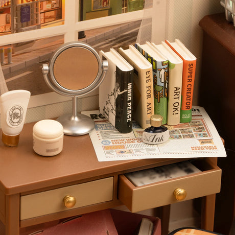 The Rolife Sweet Dream Bedroom - DIY Plastic Mini House includes a small desk with a mirror, assorted skincare items, books, and a newspaper. A slightly open drawer invites you to explore the peacefulness of this charming mini hangout by Rolife.