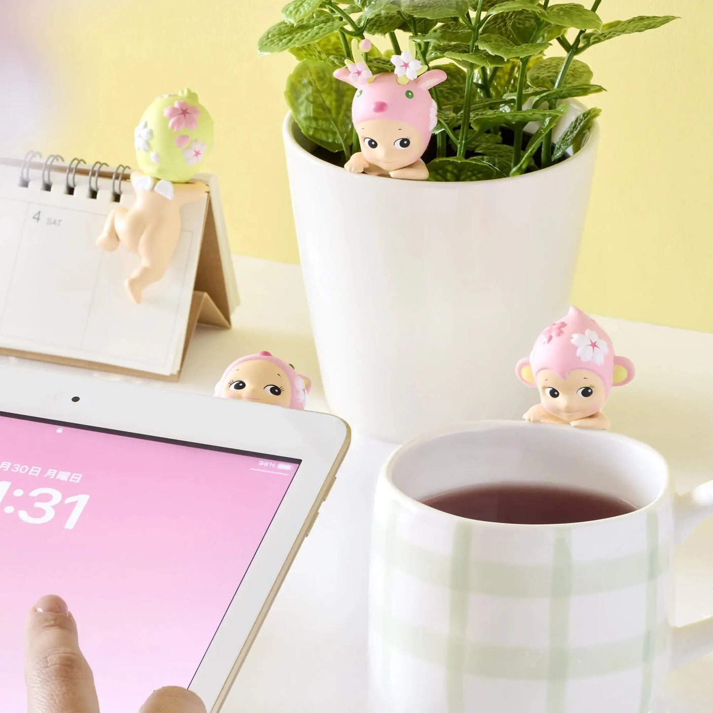 Cherry blossom bunny-hat hippers peeking near calendar, planter, and mug
