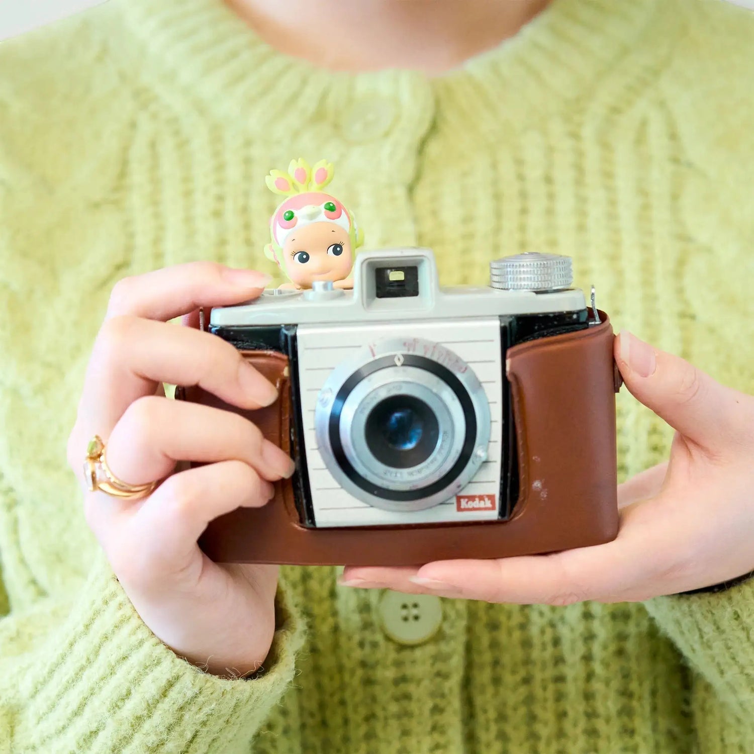 Small Sonny Angel Hippers figurine perched on top of a brown camera