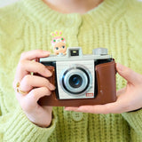 Small Sonny Angel Hippers figurine perched on top of a brown camera