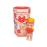 A Sonny Angel Japanese Good Luck mini figure, crafted by Sonny Angel, holds a red fish and stands proudly beside its vibrant packaging. The packaging features images of other figures and reads "Sonny Angel Japanese Good Luck," encapsulating the spirit of good fortune and charm.