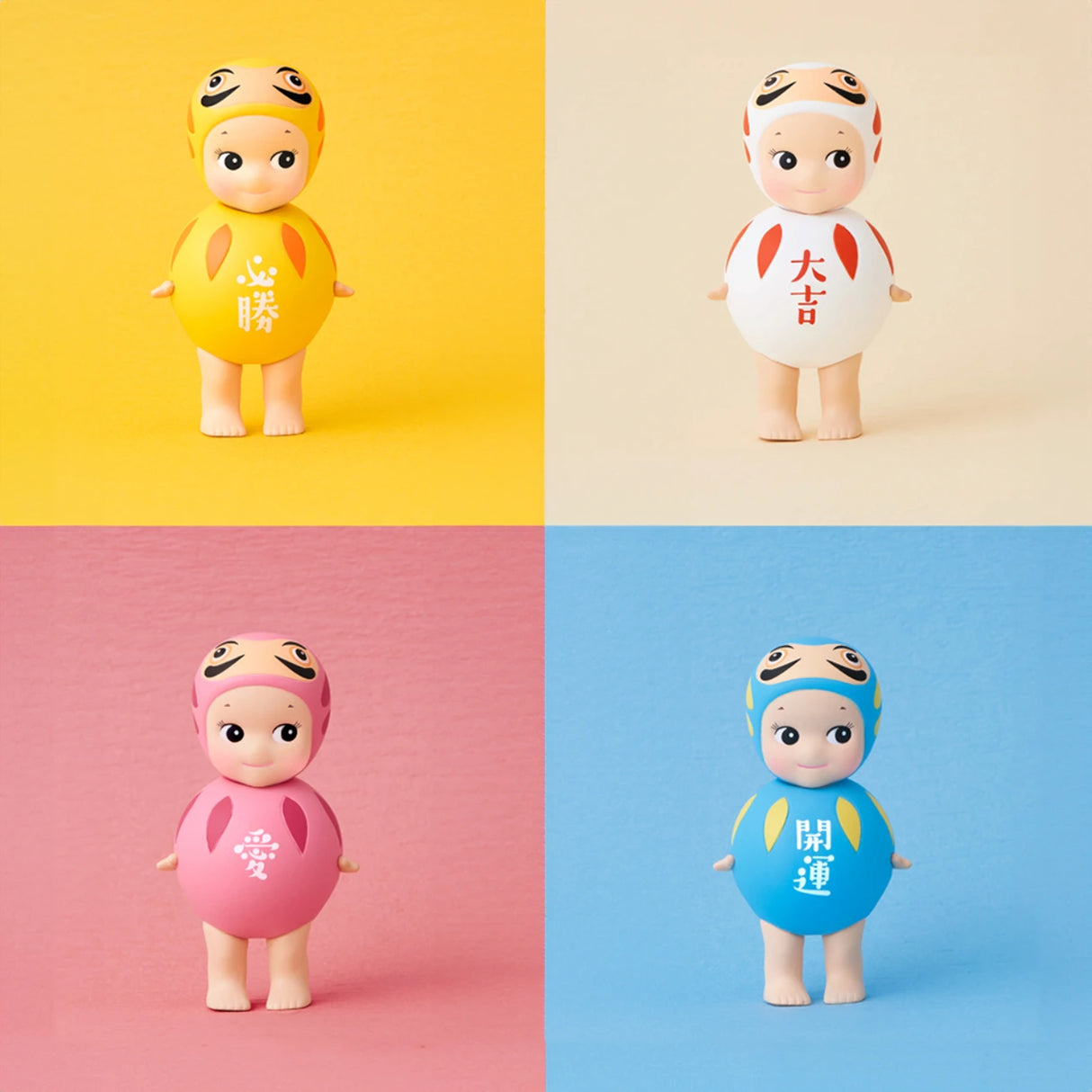 Four Sonny Angel Japanese Good Luck figures, each wearing a vibrant outfit in yellow, white, pink, or blue, stand on a split-color backdrop. Each figure's outfit is adorned with unique symbols inspired by Japanese Lucky Charms, representing good fortune.