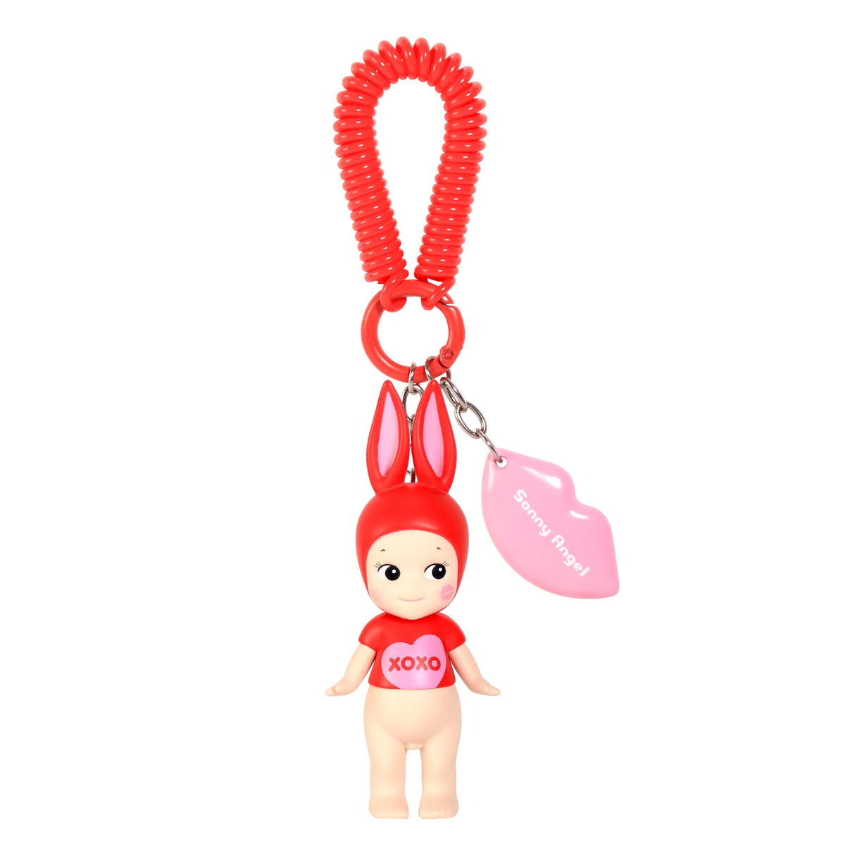 The Sonny Angel Kiss Kiss Series - Blind Box includes a keychain with a small doll in a red bunny costume and "XOXO" on its shirt, plus a pink lip-shaped tag and red coiled loop, offering the surprise of discovering which adorable Sonny Angel you'll receive!.