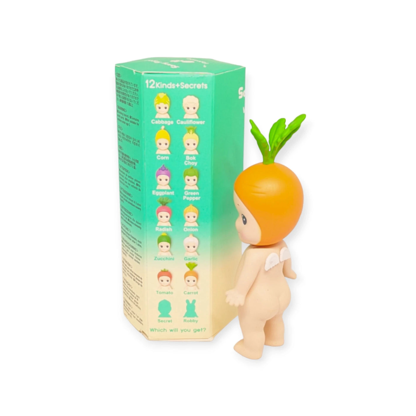 A Sonny Angel toy figure featuring an orange on its head is placed beside a green box from the Sonny Angel Vegetable Series Blind Box collection. This captivating blind box includes a variety of figures, each named after distinct fruits or vegetables, making it ideal for enthusiasts of the Vegetable Series.