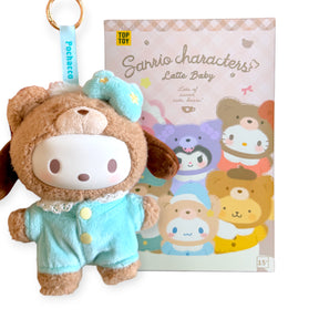 Plush keychain of a white-faced character dressed in a brown bear suit with blue pajamas and matching bow next to pastel box