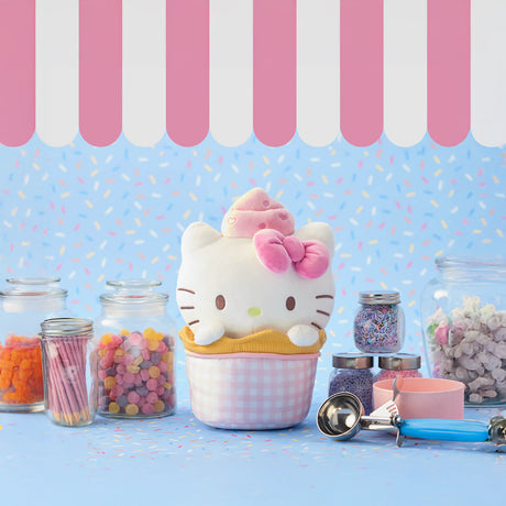 The Hello Kitty Plush - Ice Cream Sundae features an adorable Hello Kitty with a bow and cupcake, sitting in a pastel-striped cup. Surrounded by jars of colorful candy and a metal ice cream scoop against a sprinkle-patterned background, it's a charming addition to any Hello Kitty collection.