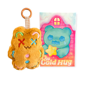 Small orange plush keychain with colorful stitched face and buttons next to a blue bear illustration on pink background