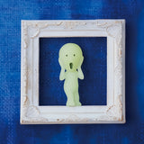 A small, glow-in-the-dark figure mimicking "The Scream" is nestled inside an ornate white frame against a textured blue background, reminiscent of a mysterious Smiski Series 1 - Blind Box treasure by Smiski.