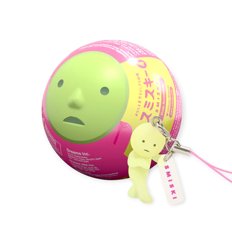 Pink and green capsule with a Smiski face, with a series 4 mini smiski figure strap keychain to the right showing the blind box capsule context. 