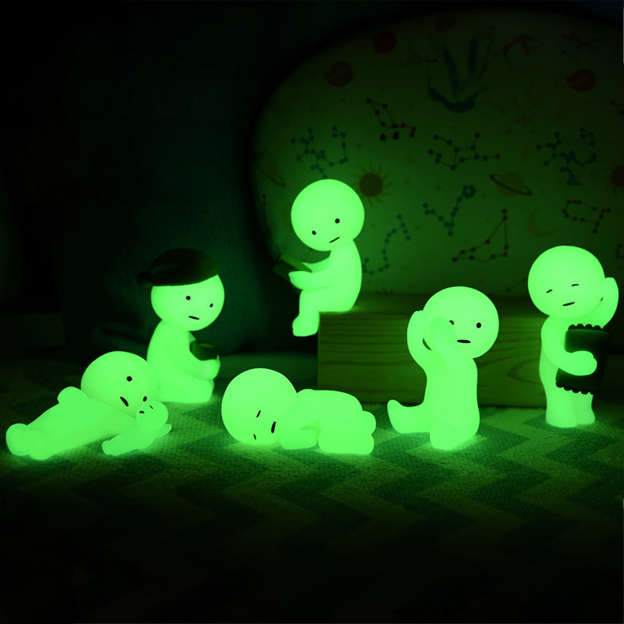 Whimsical glow-in-the-dark bedtime buddies, the Smiski Bed Series - Blind Box figures by Smiski, display playful poses against a dark background with their cartoonish glowing green appearance.