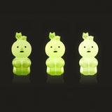 Three mint-green Smiski touch light figures in hugging knees pose, glowing
