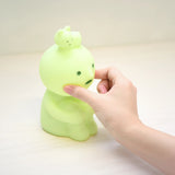 Mint-green Smiski touch light figure hugging knees, with hand touching the head
