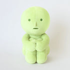 Light green Smiski Plush figure sitting with arms wrapped around knees on plain white background
