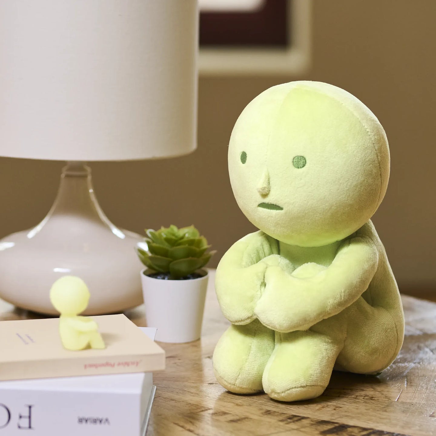 Lime-green Smiski hugging knees plush figure with crossed arms, stitched face