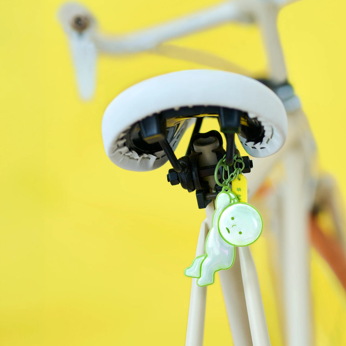 Reflective green Smiski charm hanging from backpack zipper pull