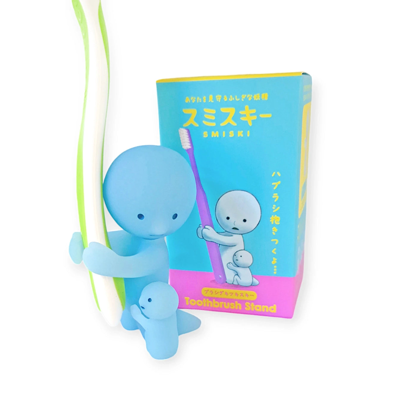 A Smiski Toothbrush Holder - Hugging Figure, notable for its collectible appeal, gently supports a toothbrush and emits a subtle glow in the dark. The original packaging stands prominently in the background, adding to its allure.