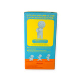 A Smiski Toothbrush Holder - Holding Figure with a cartoon face is positioned on a yellow and blue box. Text in Japanese and English describes this glow-in-the-dark product, making it perfect for keeping your bathroom organized.