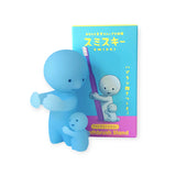 The Smiski Toothbrush Holder - Hugging Figure from the brand Smiski is a glow-in-the-dark collectible that showcases a blue figure embracing a toothbrush, with its appealing packaging visible in the background.