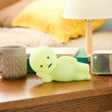 Smiski Touch Light lounging figure, light green, on a bedside table