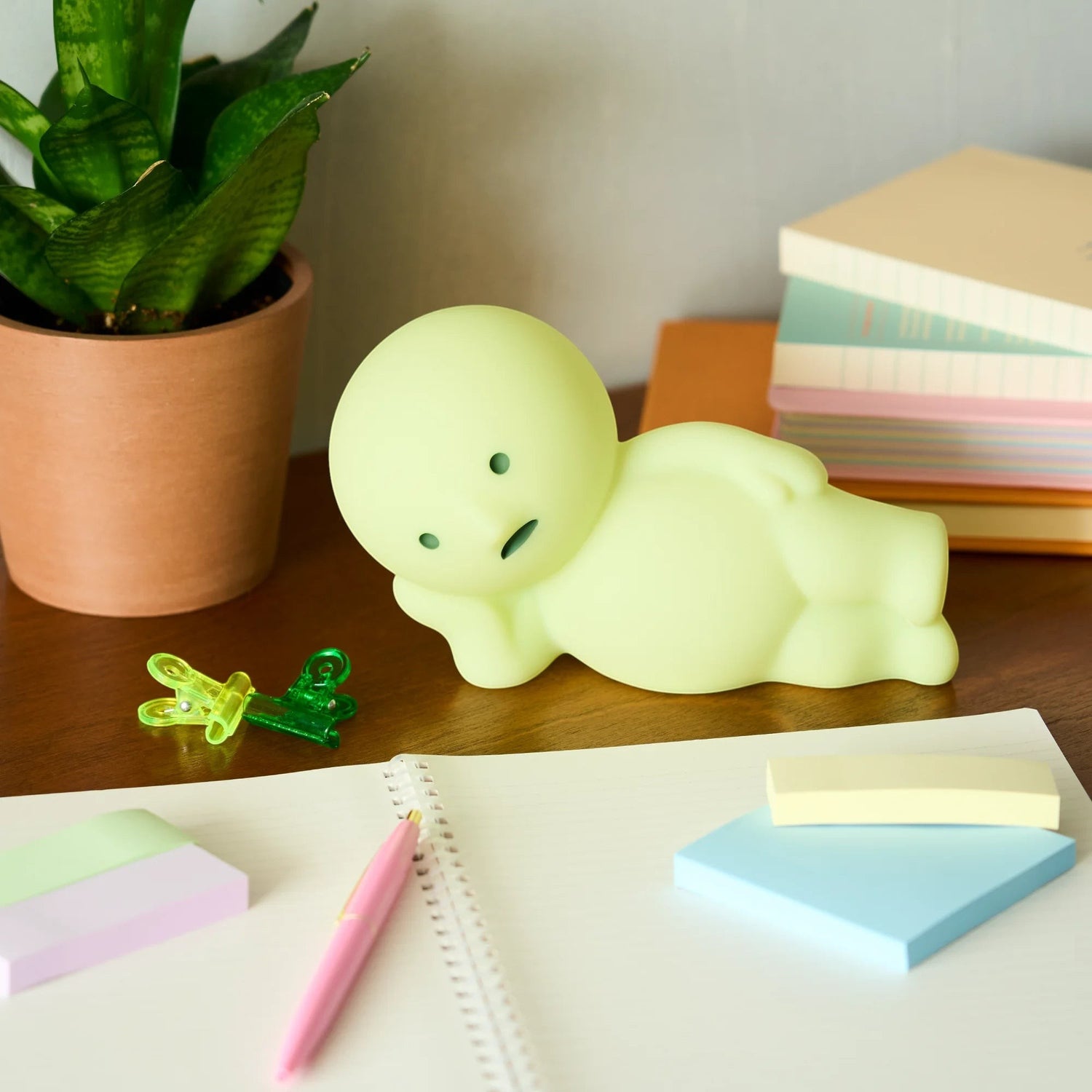 Smiski Touch Light lounging figure, light green, on a desk among stationery