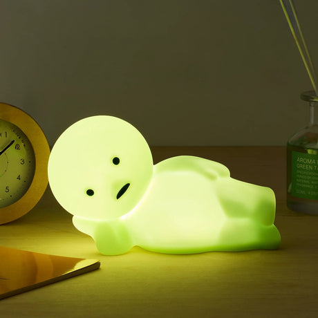 Smiski Touch Light lounging figurine, light-green glow on tabletop at night